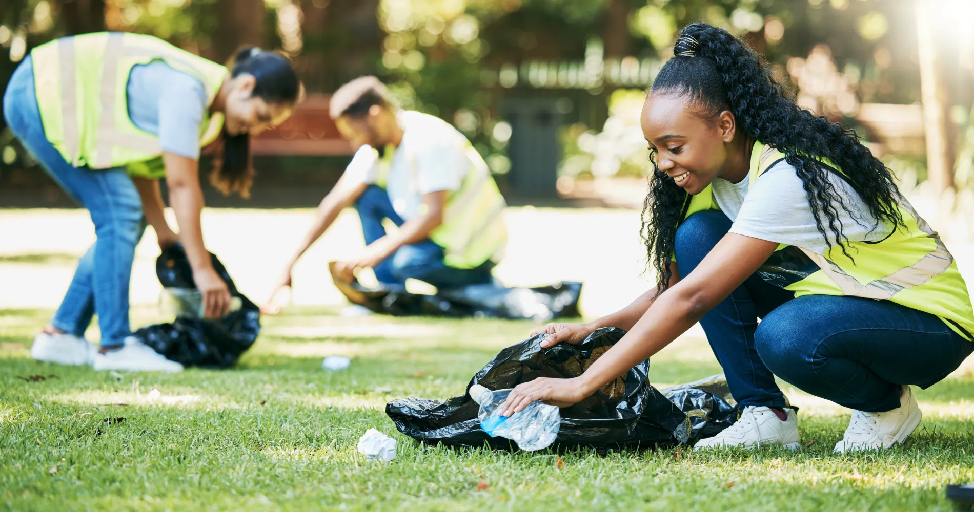 volunteer-people-cleaning-park-community-service-clean-environment-recycling-pollution-black-woman-happy-help-group-with-plastic-bottle-trash-bag-outdoor-green-environment 1